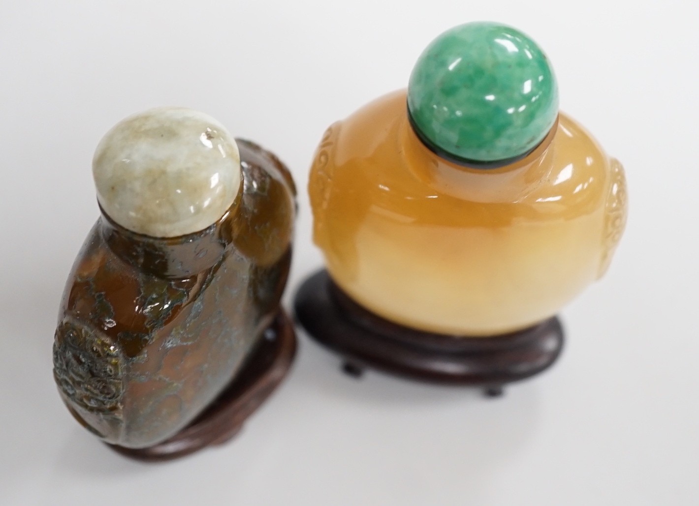A Chinese honey coloured agate mask and ring handled snuff bottle and a dendritic chalcedony (moss agate) mask and ring handled snuff bottle, 5.7cm, both 1780-1880